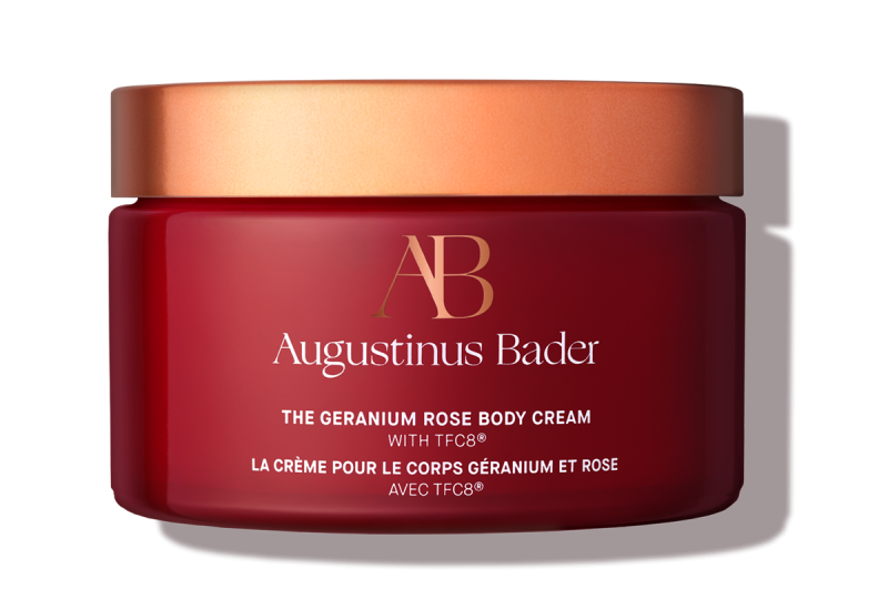 Red jar of Augustinus Bader body cream with a gold lid on a white background