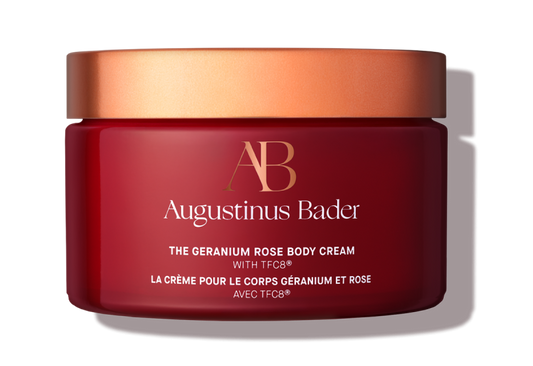 Red jar of Augustinus Bader body cream with a gold lid on a white background